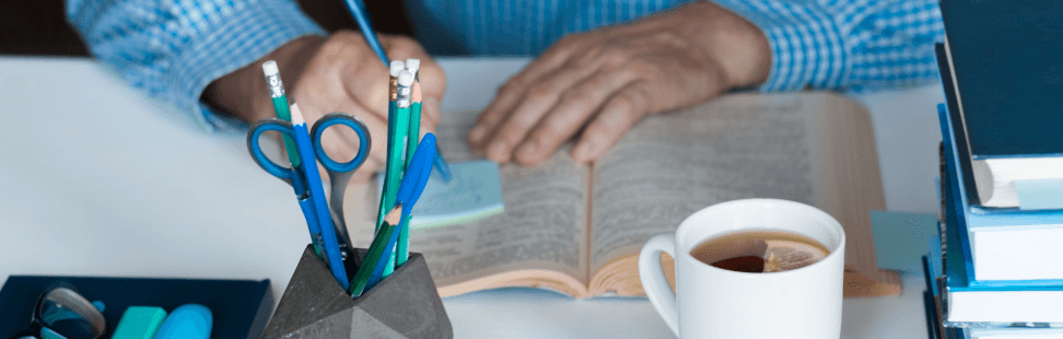 A man taking notes on an open book.png