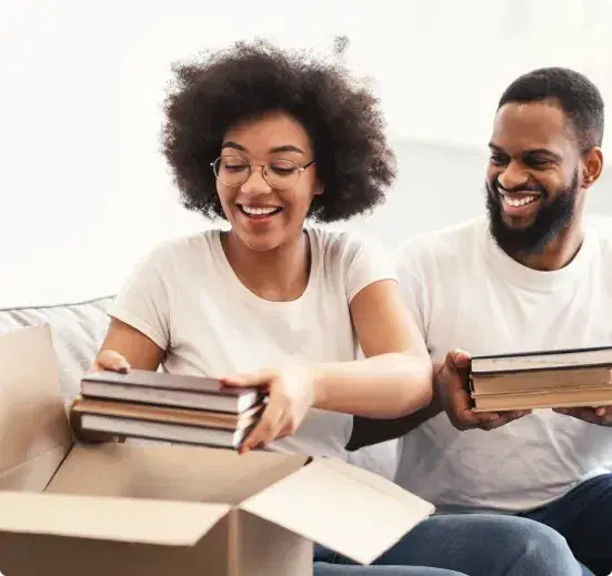 Smiling couple packing books into a box to sell to WeBuyBooks for cash