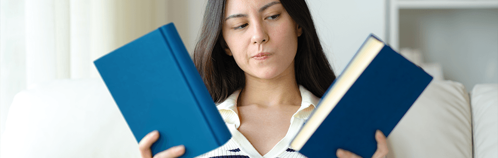 A woman choosing between two blue books.png