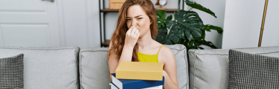 A woman holding her nose because of bad smelling books.png