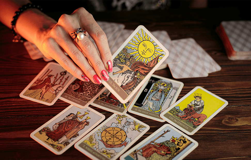 A woman picking up a card from a pile of tarot cards.png