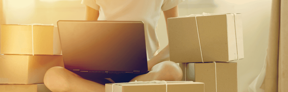 A woman sat with a laptop on her lap selling books in boxes.png