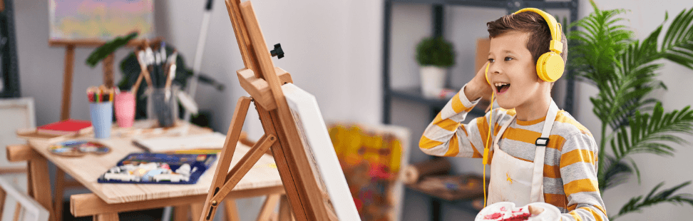 Child listening to a Yoto player while painting.png