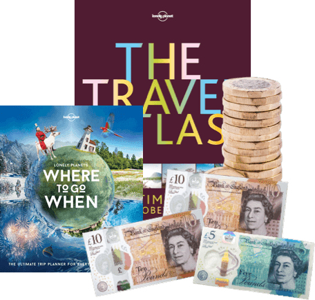 Travel guides 'Where to Go When' and 'The Travel Atlas' with UK banknotes and coins for cash