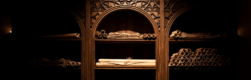 Old building scrolls on wooden shelves in a dark room.png