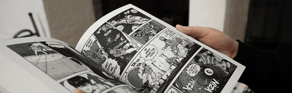 Person in a black jumper reading an open manga.png
