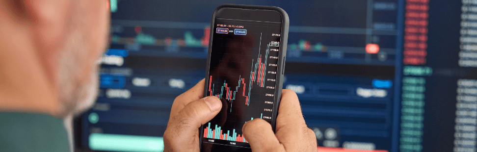 a man investing in stocks and shares on his mobile phone.png