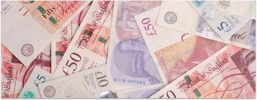 Scattered British banknotes, illustrating the cash WeBuyBooks pays out with next day payments