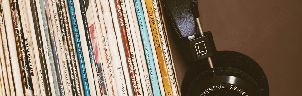 pair of vintage headphones next to a stack of vinyl records.png