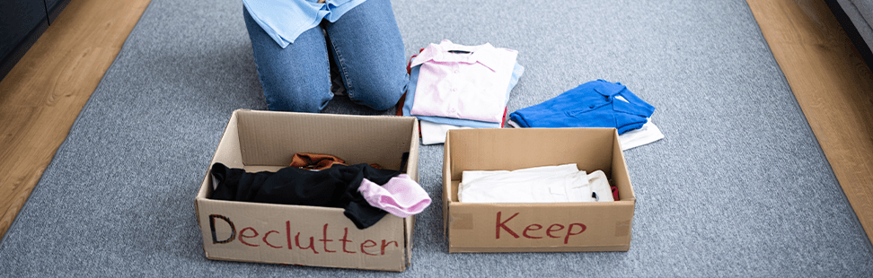 person dividing clothes into a declutter box and a keep box.png
