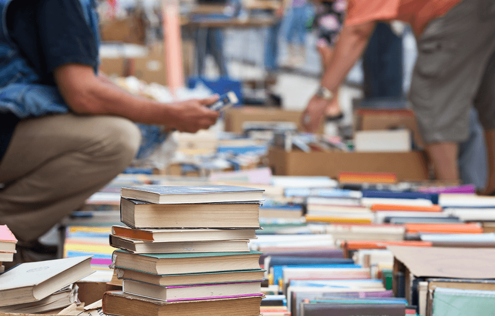 two people searching through a second hand book sale.png