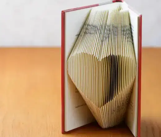 Red hardback book with pages folded into a heart shape, symbolising book recycling