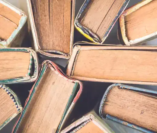 Overhead view of old hardback books with worn pages stacked together for recycling